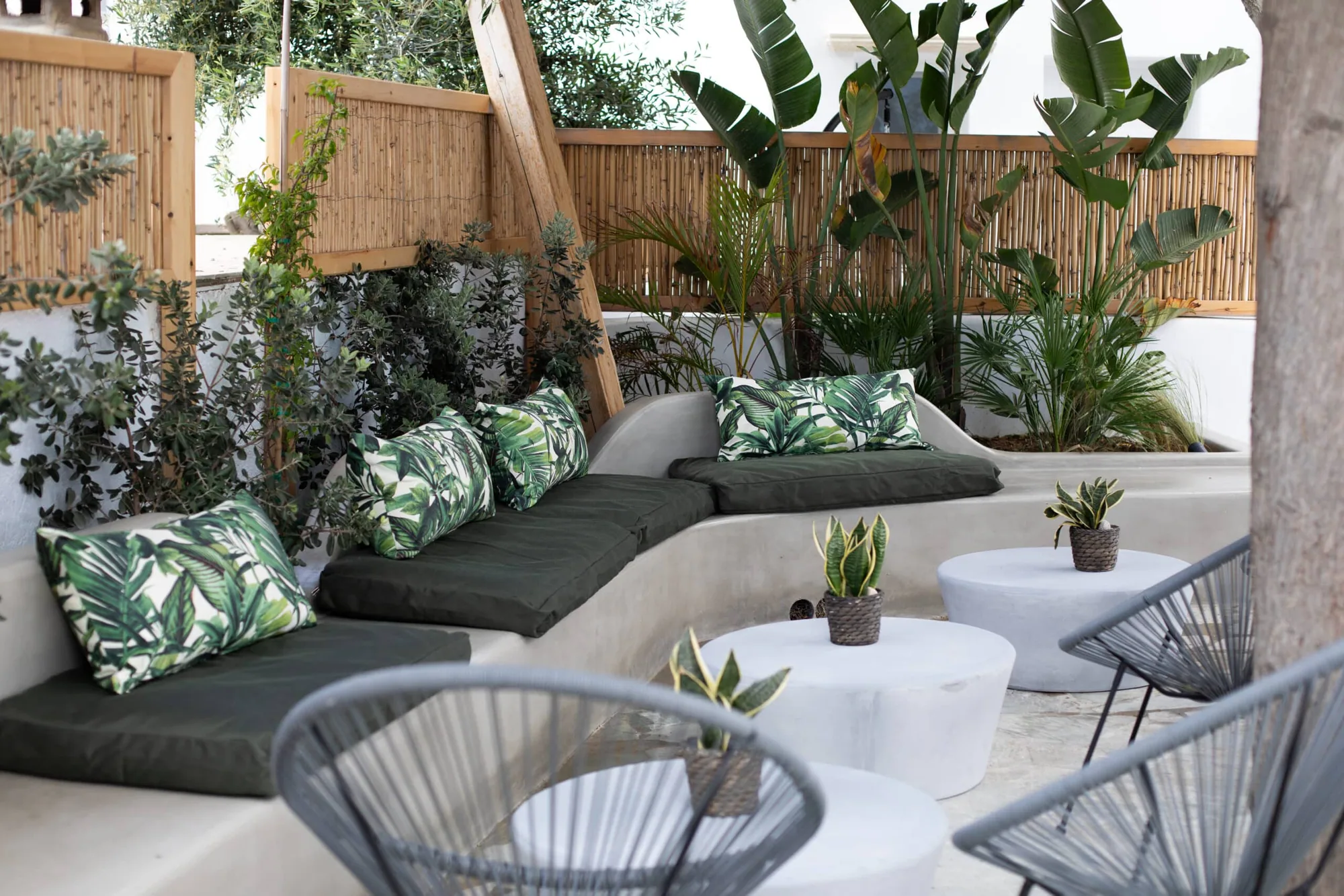 Garden lounge with leaf-print cushions and white tables